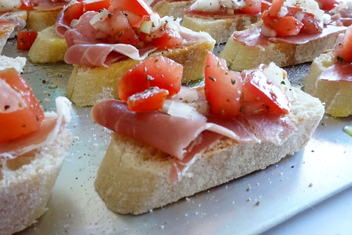 making bruschetta with prosciutto and tomatoes French baguette slices