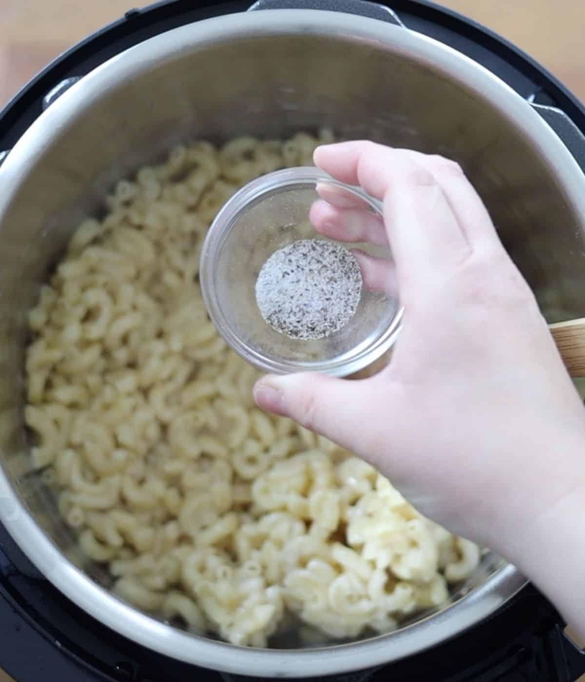 adding salt and pepper to macaroni and cheese