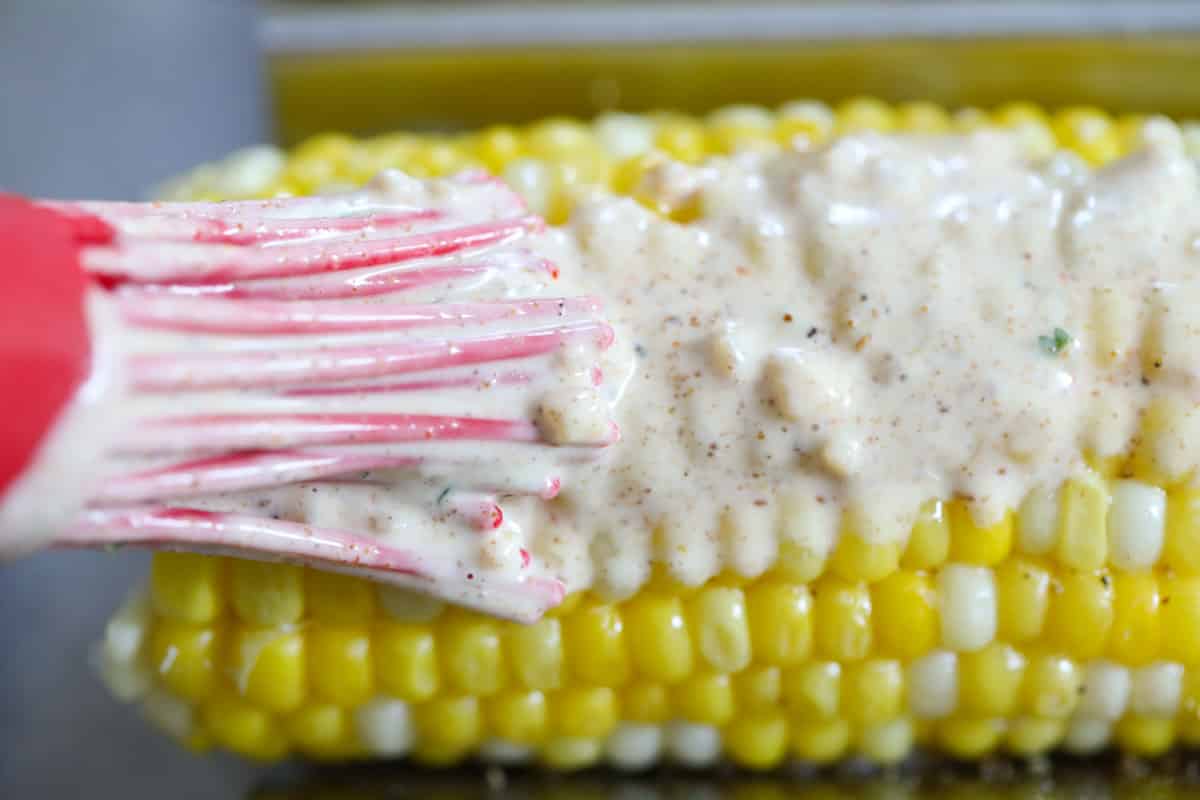 adding sauce to Mexican street corn