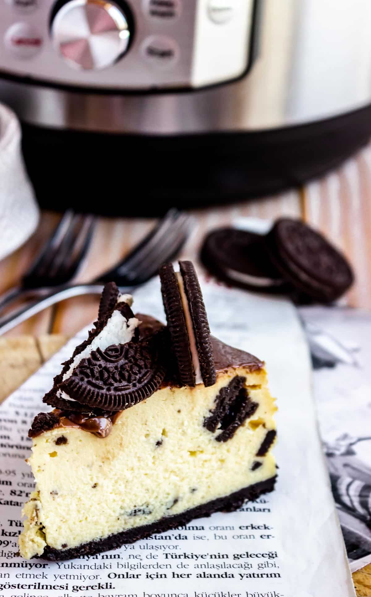 thick slice of Oreo cheesecake with the instant pot in the background