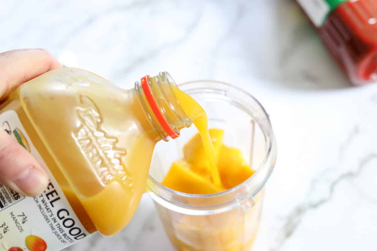 adding mango fruit juice to blender