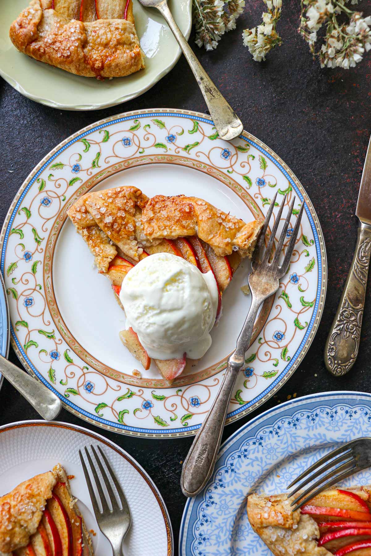 multi colored plates with apple galette slices and one in the center with ice cream