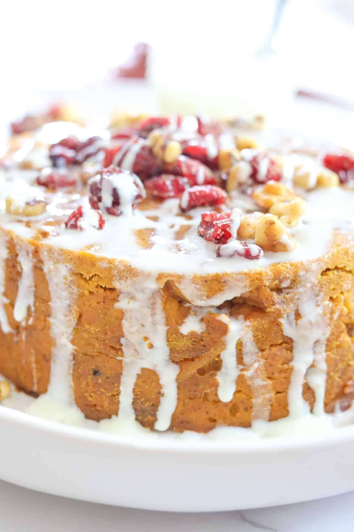 icing dripping down bread pudding with cranberries and candied walnuts
