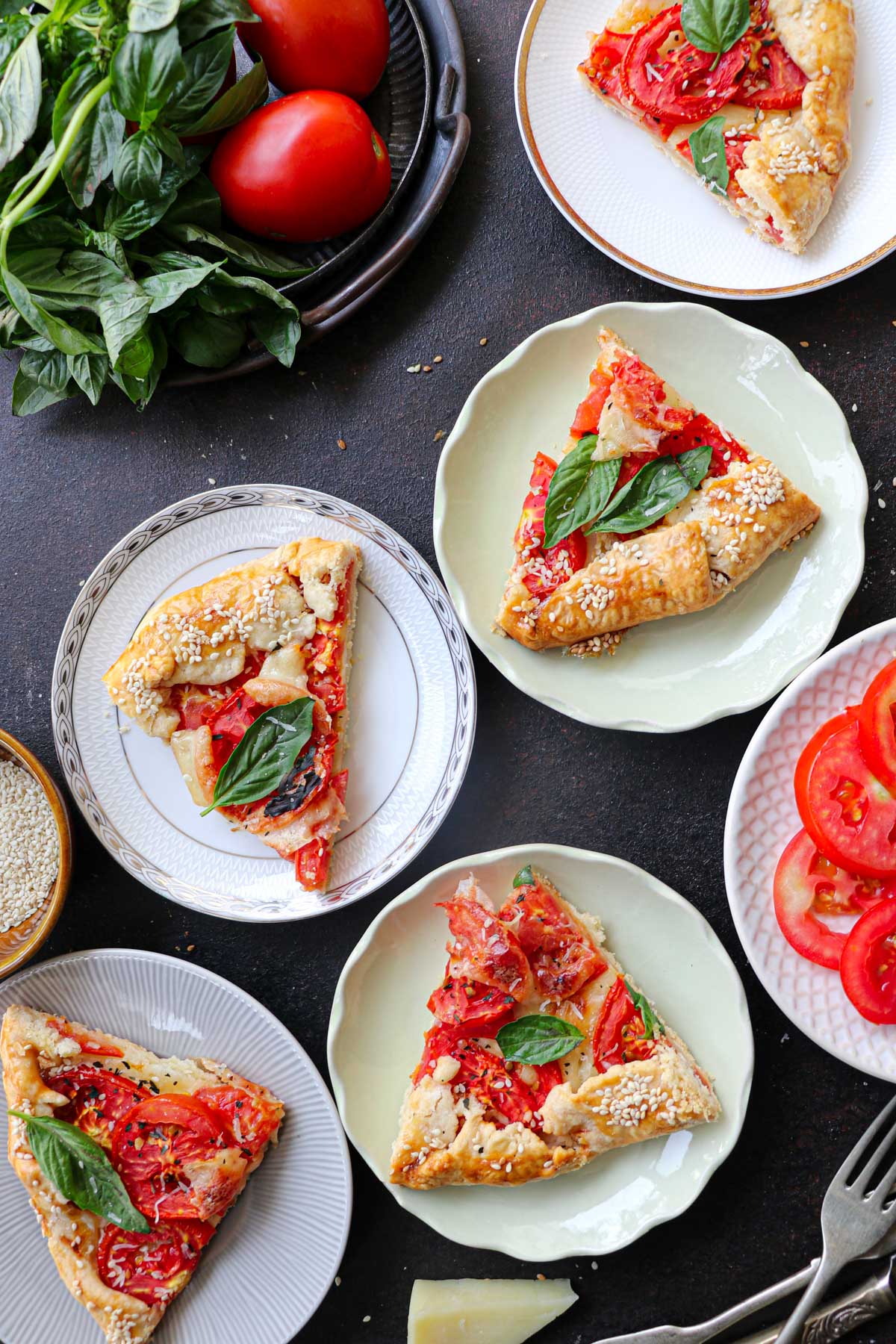 galette pieces on a variety of plates with tomato and fresh basil