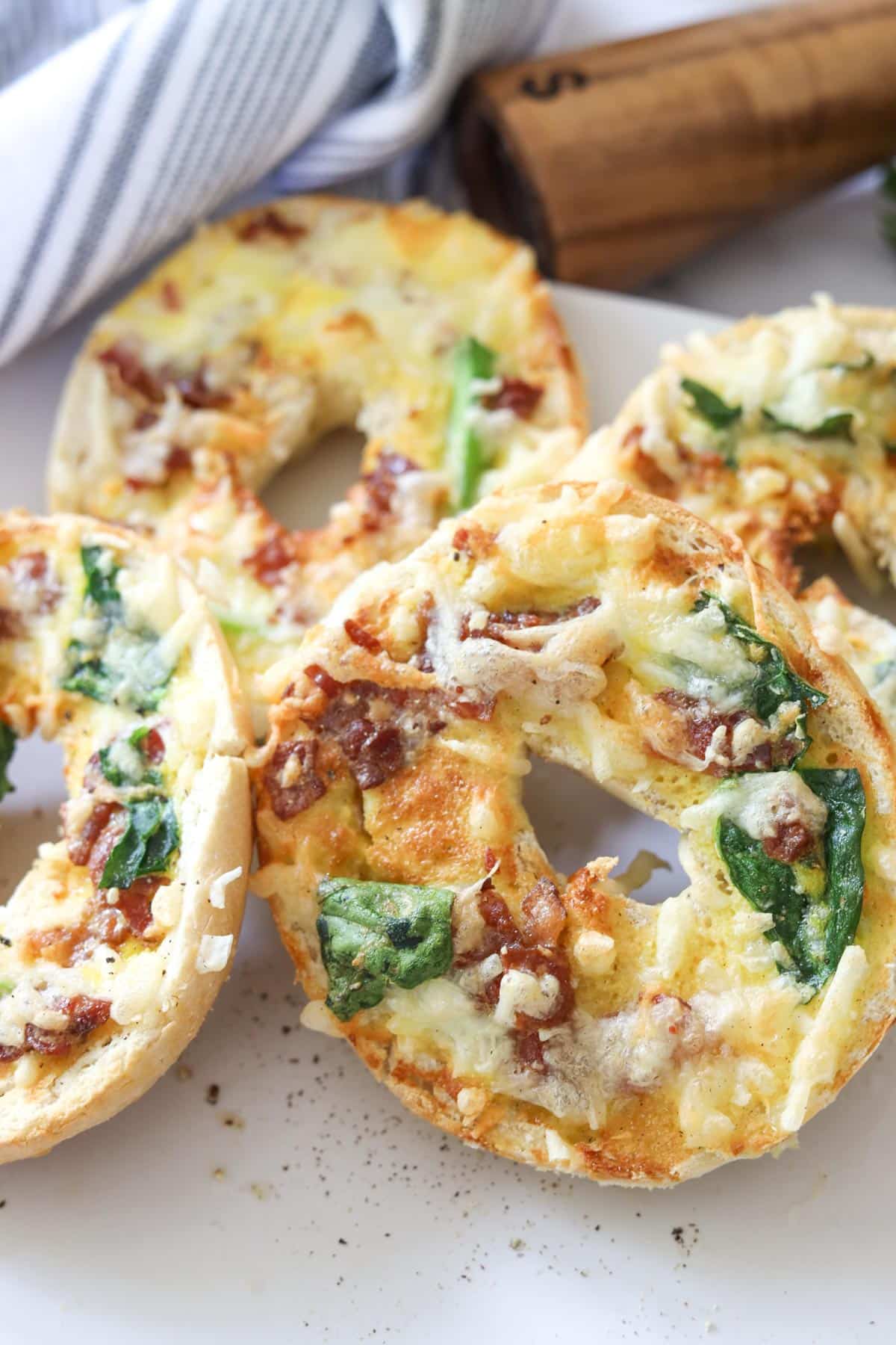 four breakfast bagel boats with spinach cheese toppings