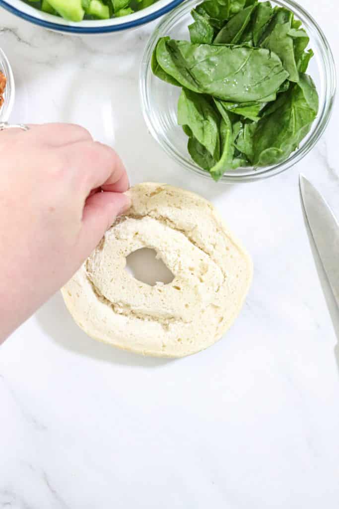 pinching inside of bagel with finger and thumb