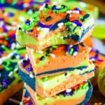 green orange and black Halloween fudge stacked in a pile with the top piece having a bite taken out