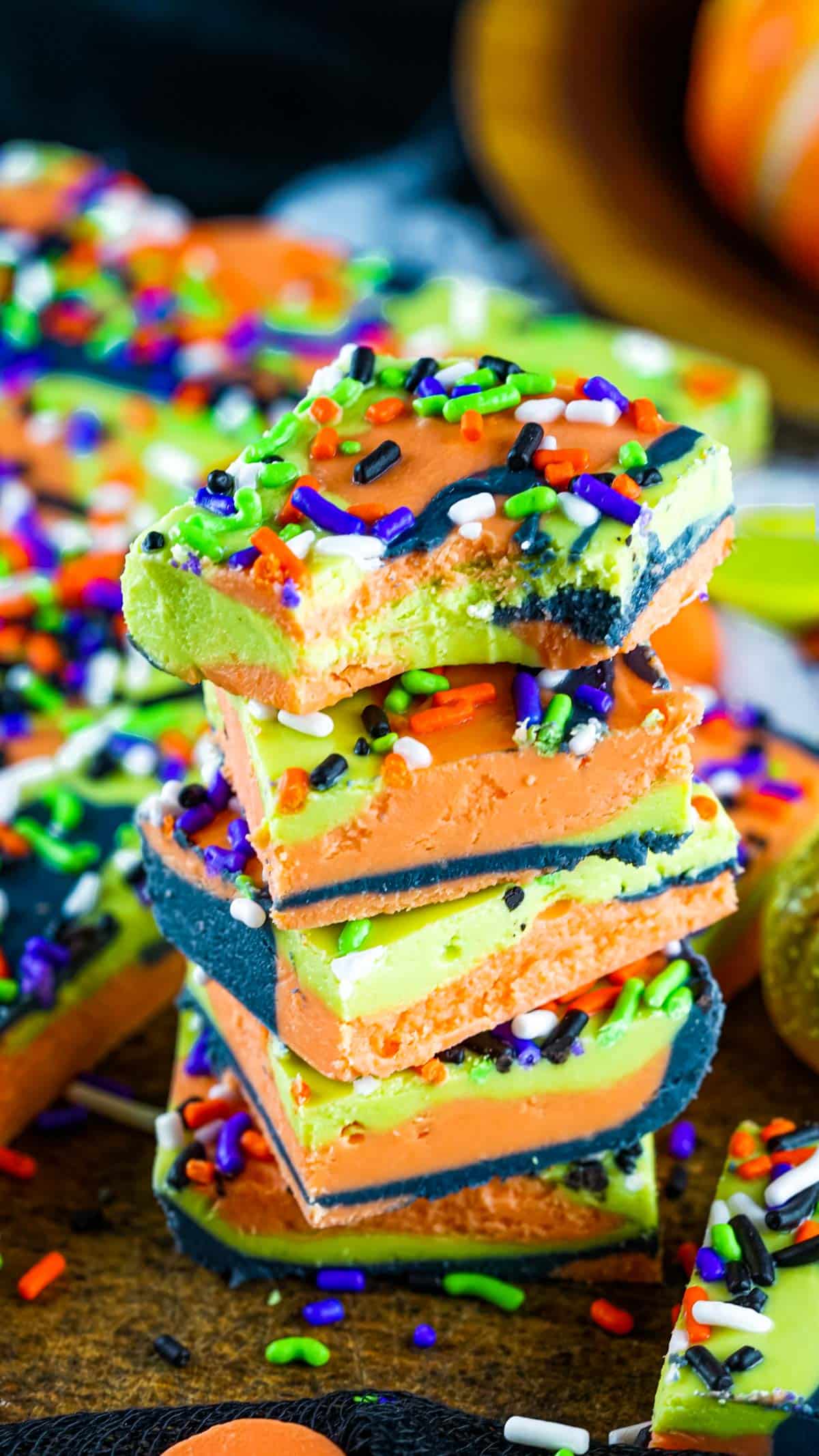 green orange and black Halloween fudge stacked in a pile with the top piece having a bite taken out