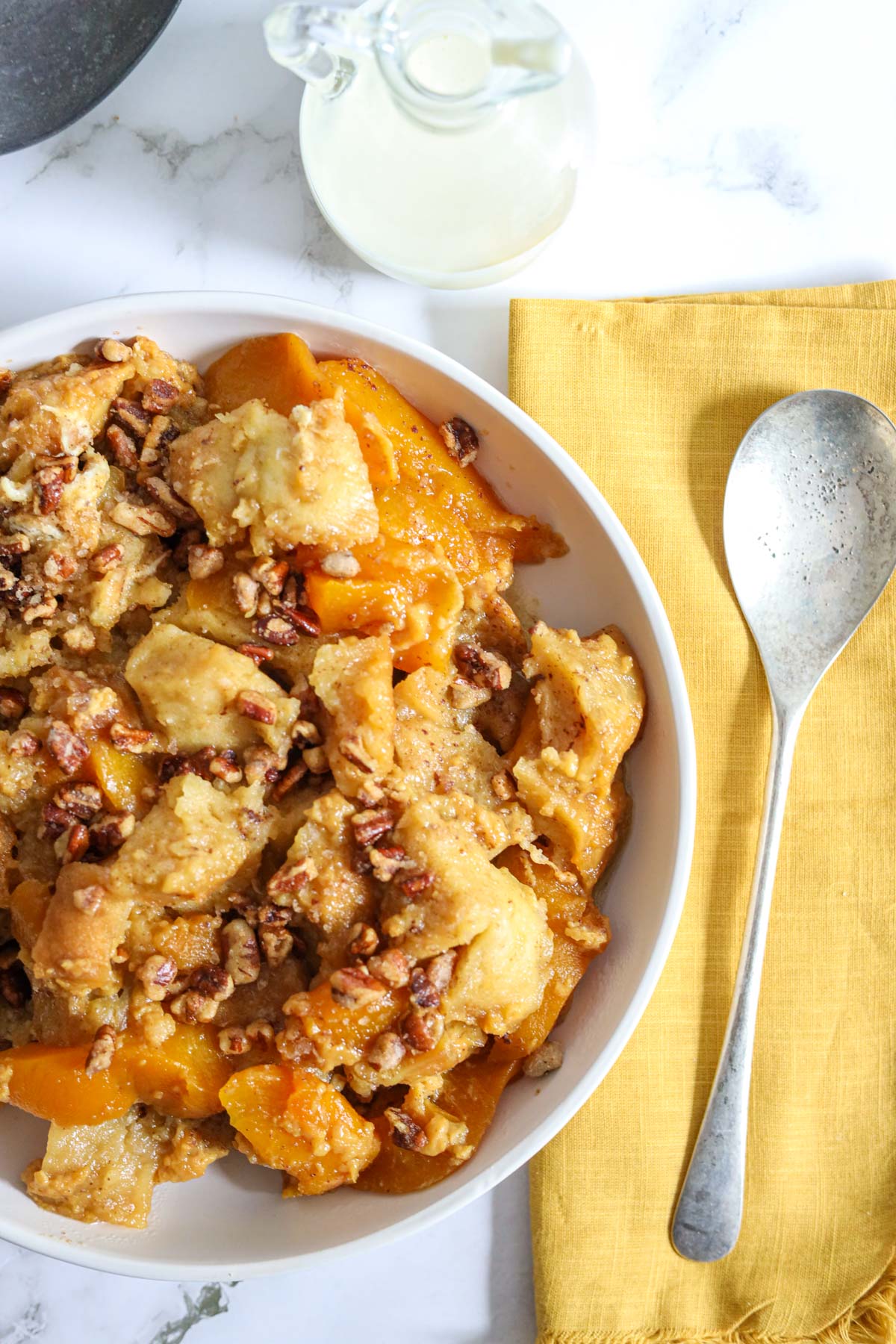 peach bread pudding on a plate with candied walnuts