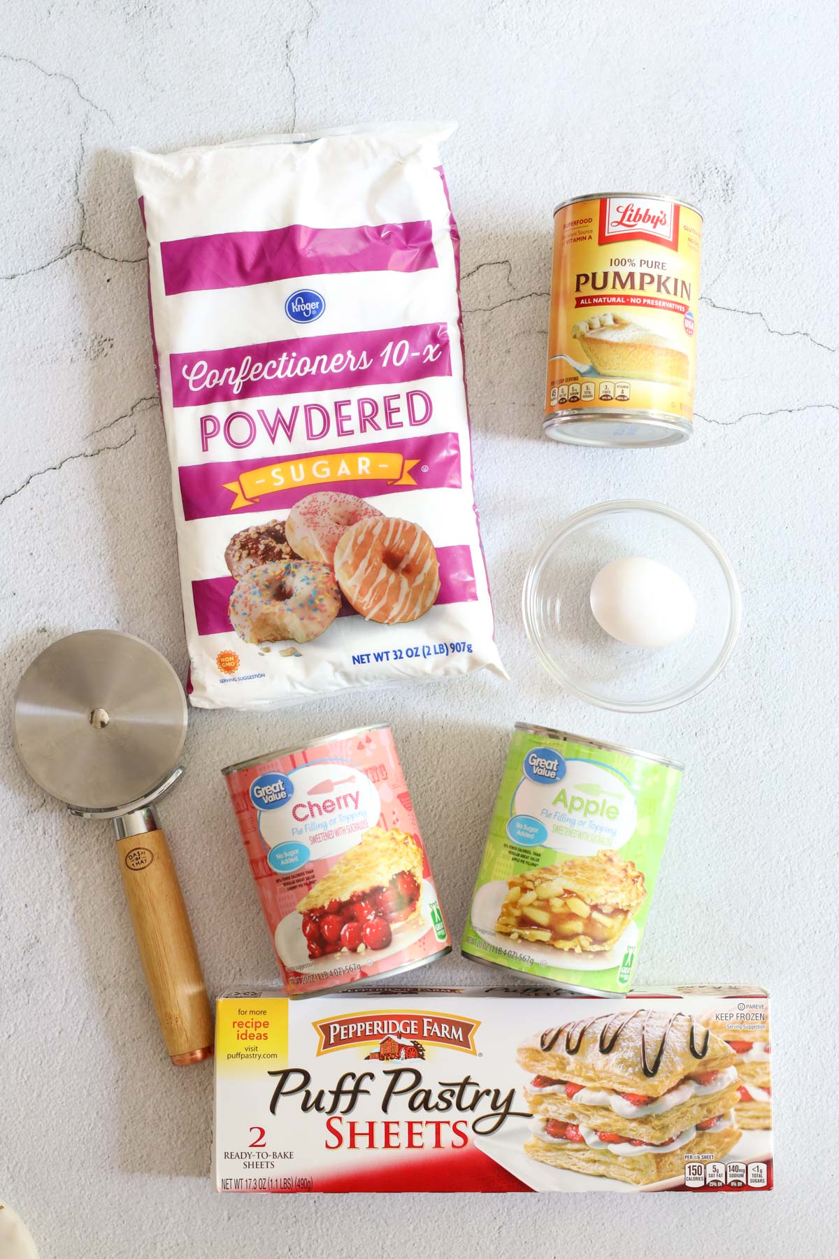 ingredients for simple air fryer turnovers including pie filling, confectioner's sugar, puff pastry