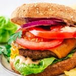 thick cheeseburger with sesame seed bun and lettuce, tomato, onion and burger sauce