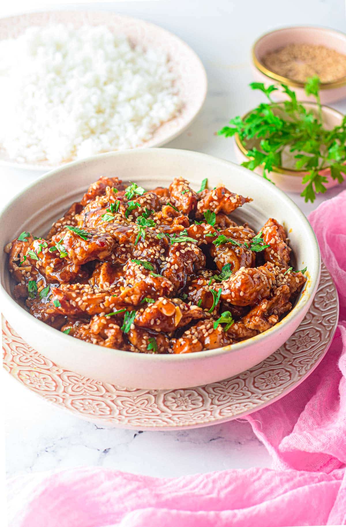 table set with rice and sesame chicken in a bowl