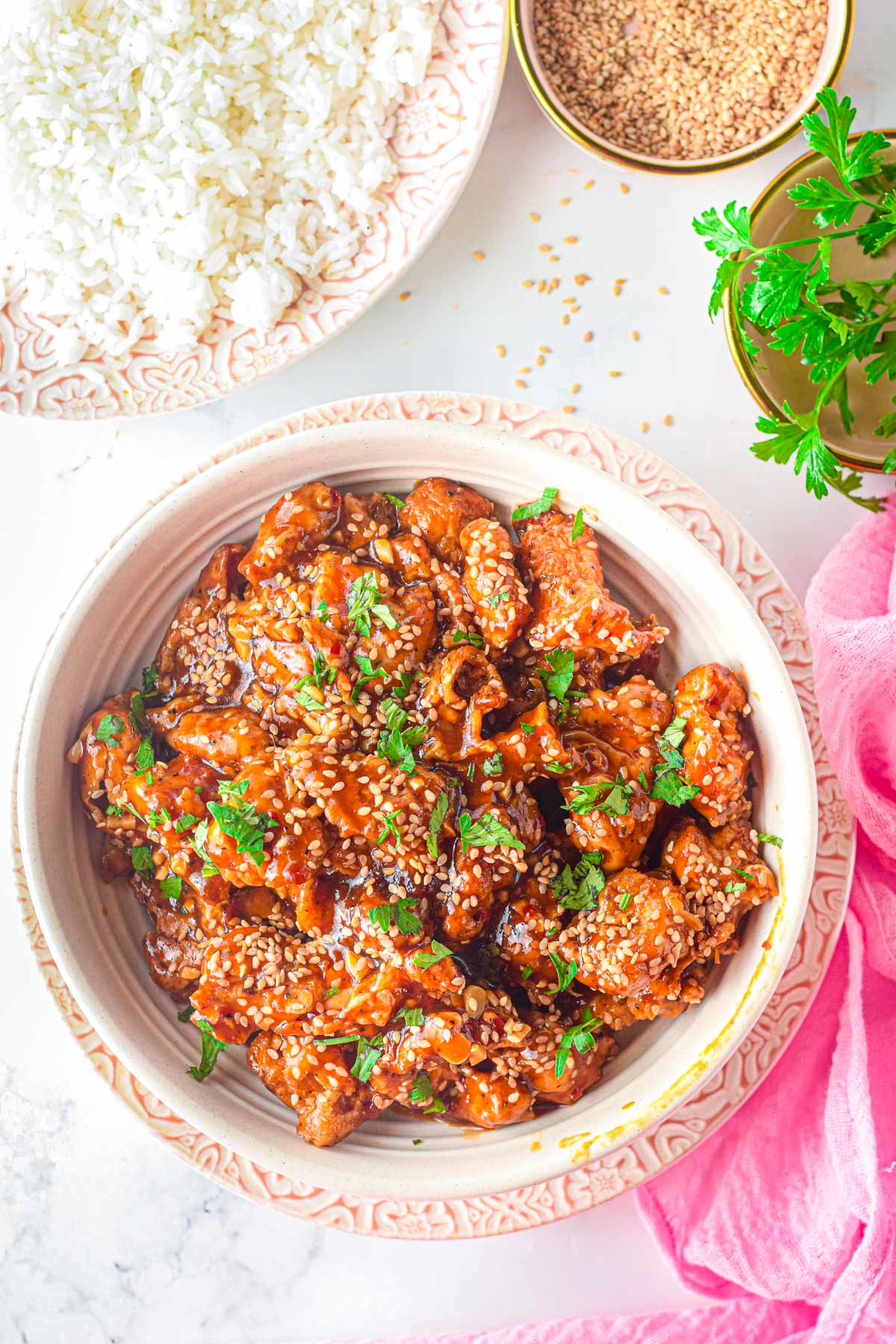 a bowl of rice served with sesame chicken and cilantro garnish