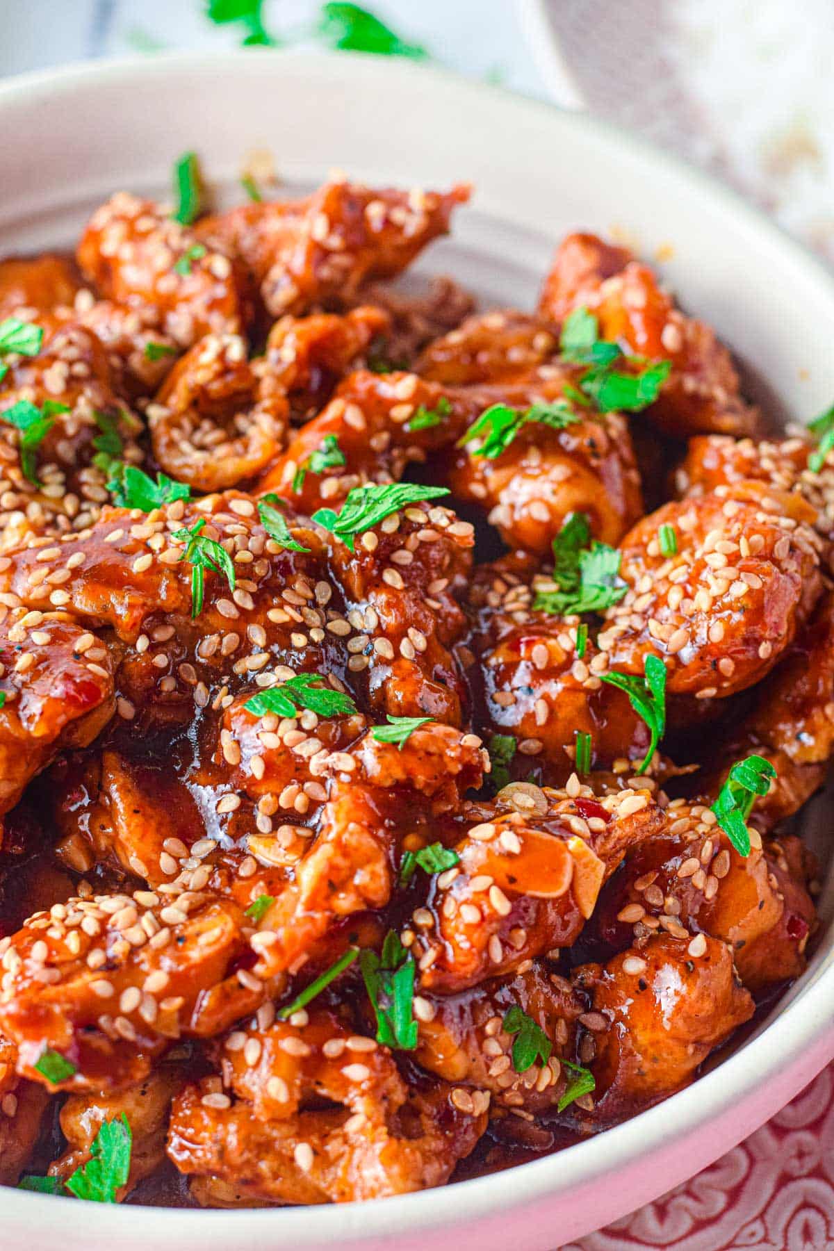 sesame chicken in a bowl with green onion garnish