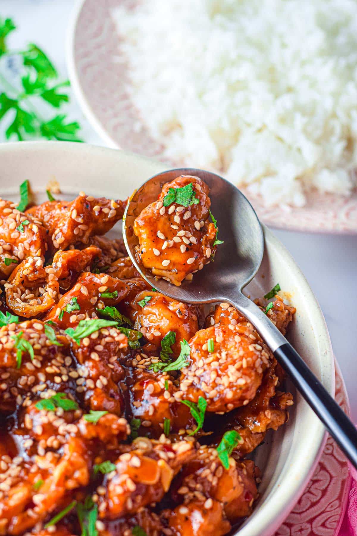 spoon scooping up a yummy bite of glazed sesame chicken