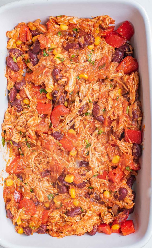 baking dish with shredded chicken, corn, beans, and tomatoes