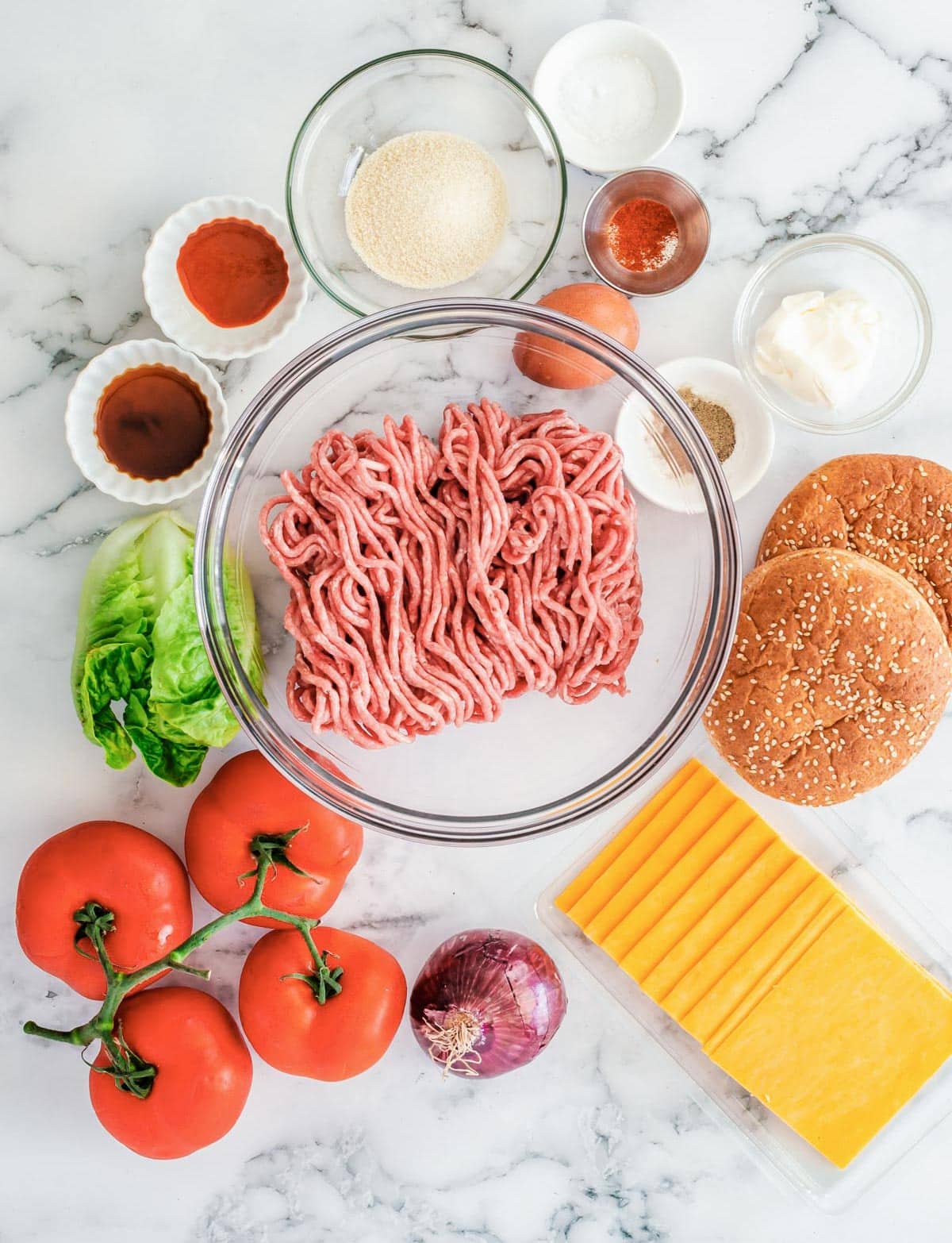 ingredients for air fryer burgers, including buns, ground beef, onion, lettuce, tomato, worcestershire sauce, mayo egg, and bread crumbs