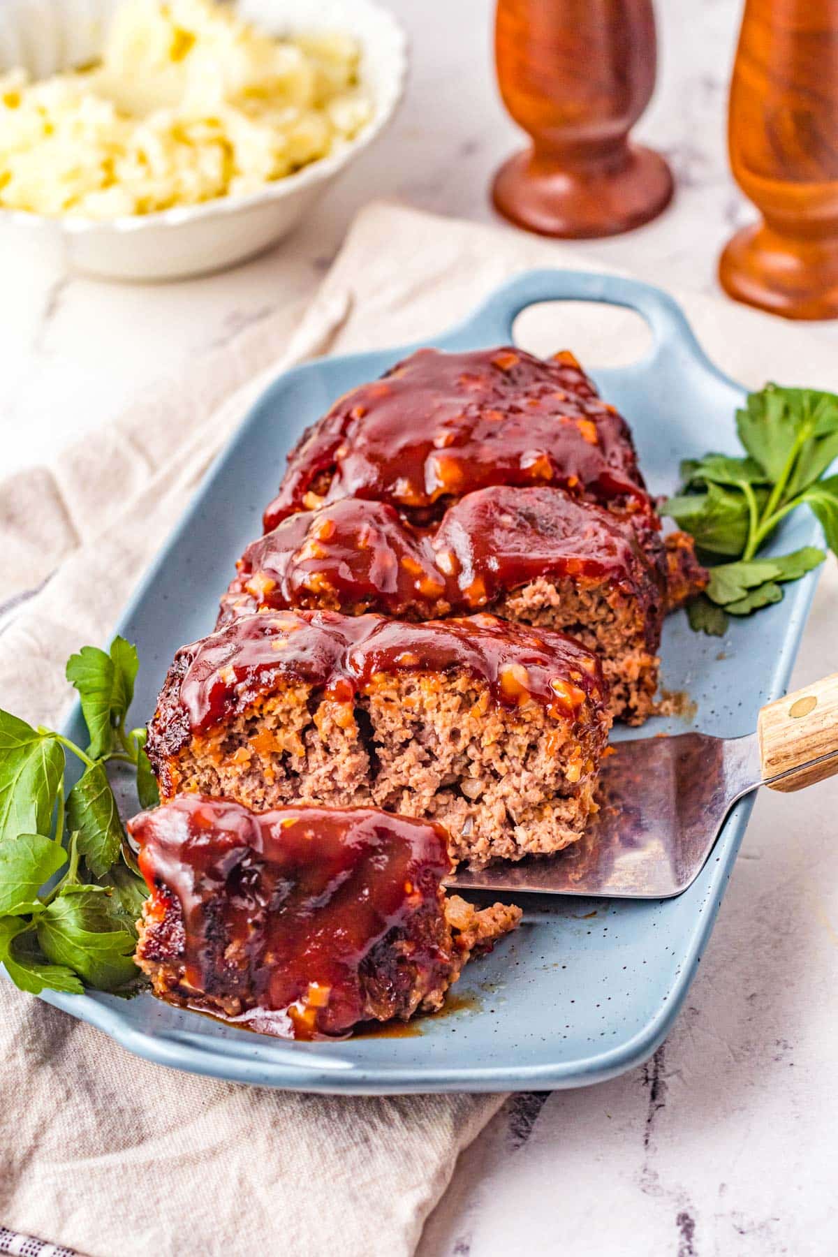 air fryer meatloaf covered in delicious sauce next to mashed potatoes and salt and pepper shakers