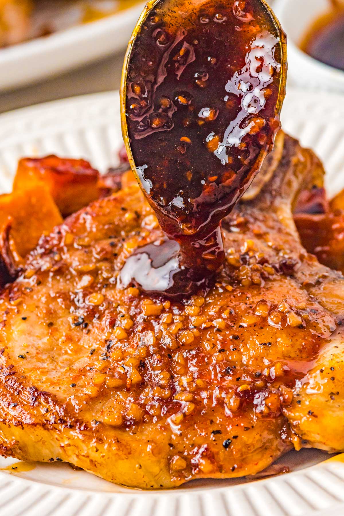 bourbon maple glaze being poured over a garlic smothered pork chop