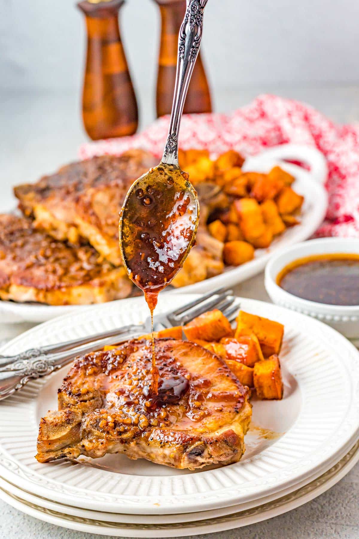 spoon pouring glaze on top of garlic roasted pork chop