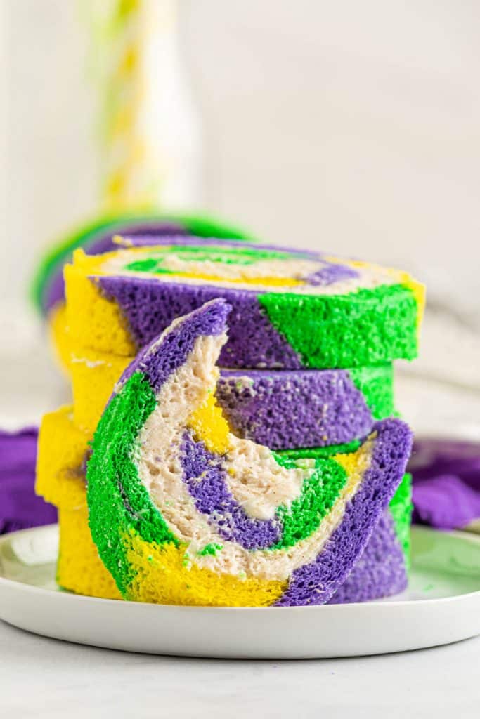 swirled Mardi Gras cake roll with yellow, green and purple and cinnamon cream cheese frosting inside