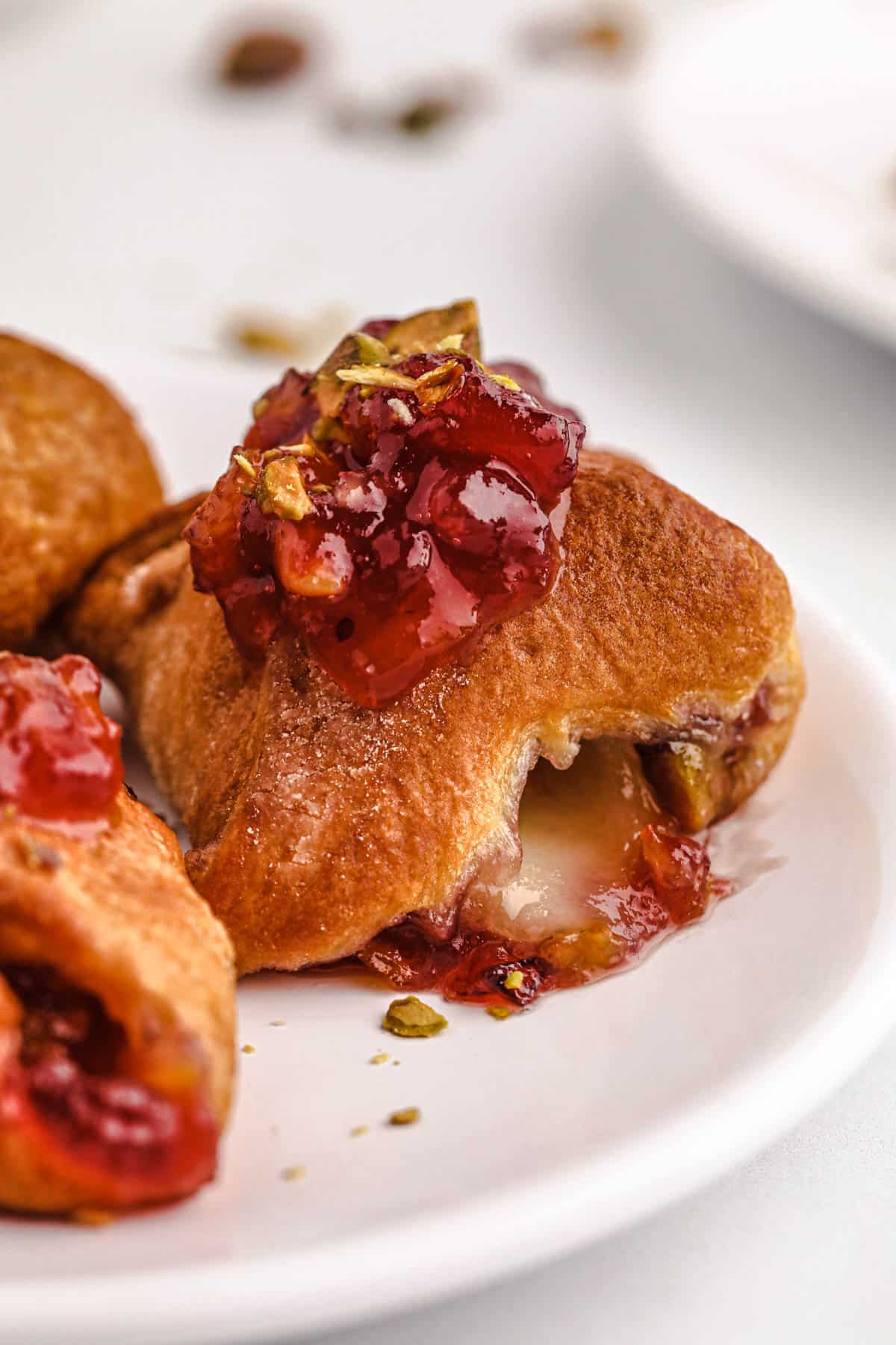 brie bite with cranberry sauce and pistachios on top