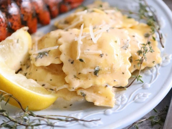 silky creamy sauce over large ravioli next to a lobster tail
