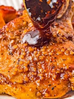 spoon pouring thick, sticky bourbon glaze on top of pork chop