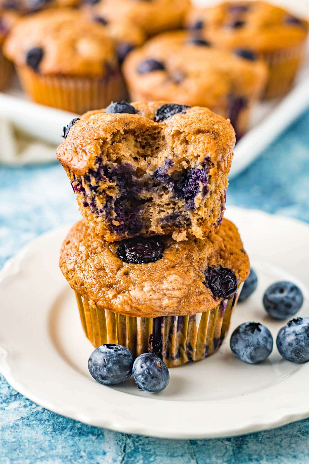 banana blueberry muffins stacked on top of each other on a white plate