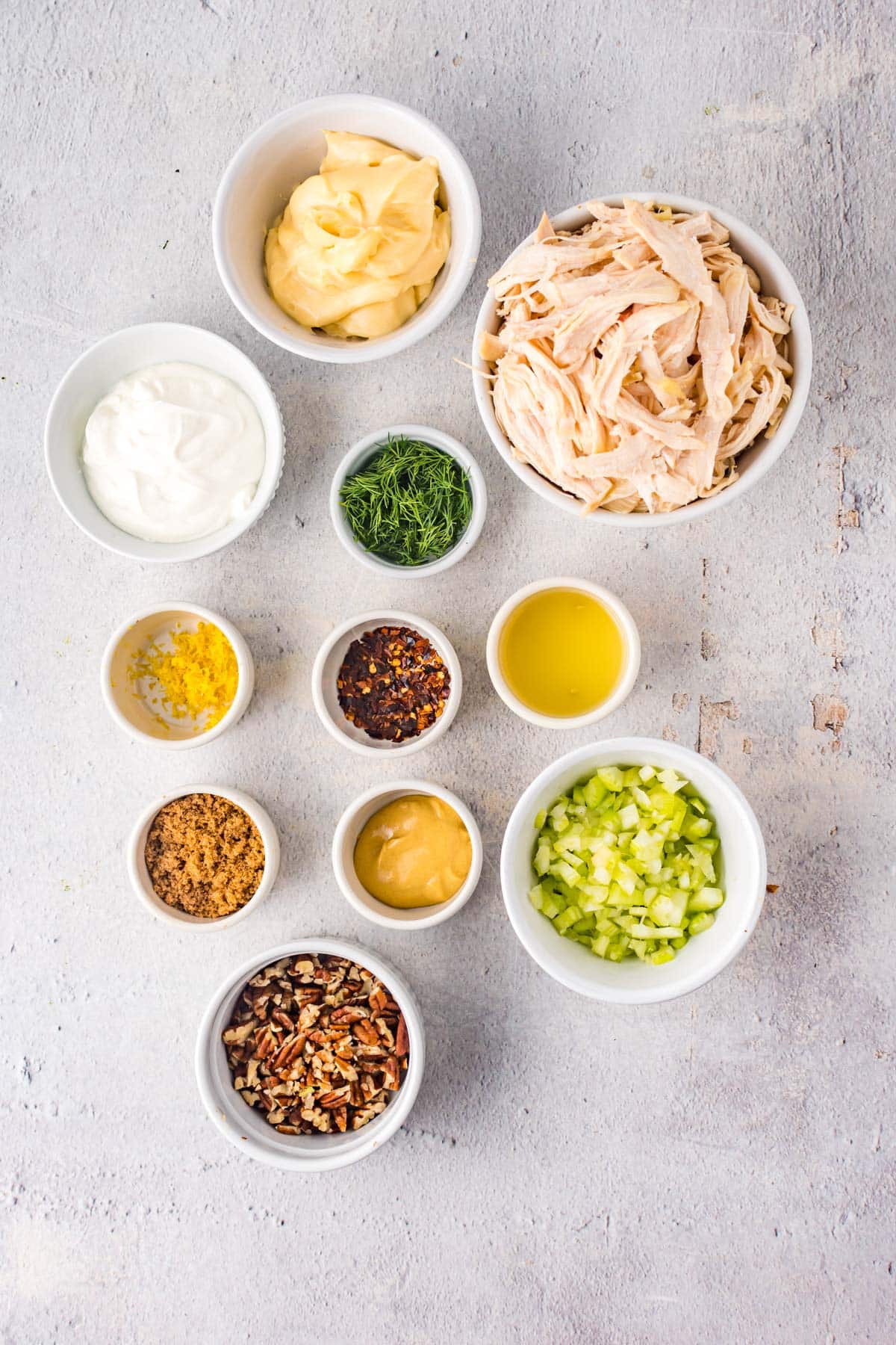 ingredients for chicken salad, including pecans, mayo, sour cream, celery, lemon zest and dill