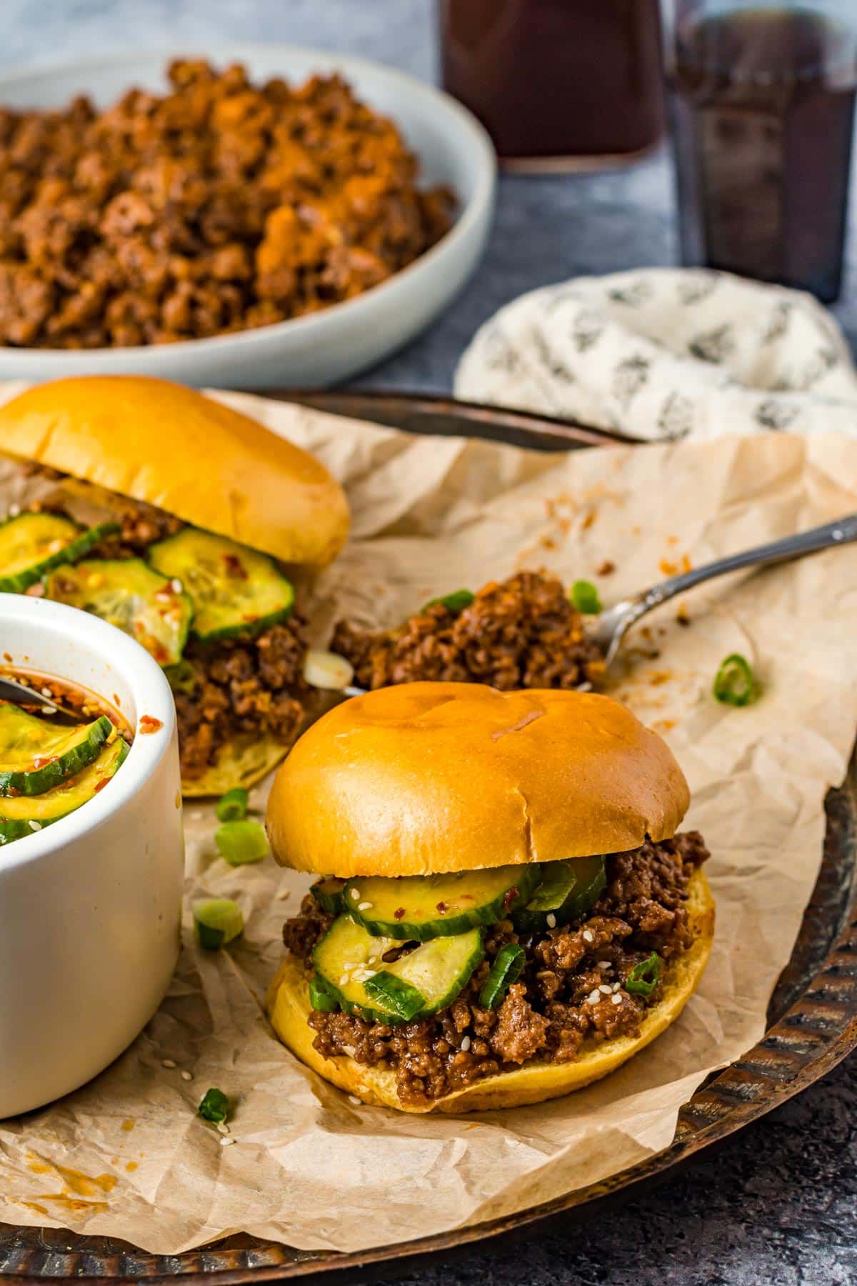 Sloppy Joe beef in a bowl next to a sloppy Joe sandwich made of Brioche on parchment paper 