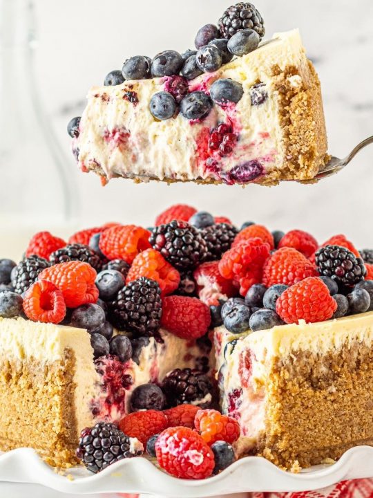 triple berry cheesecake slice with blueberries, strawberries, and blackberries