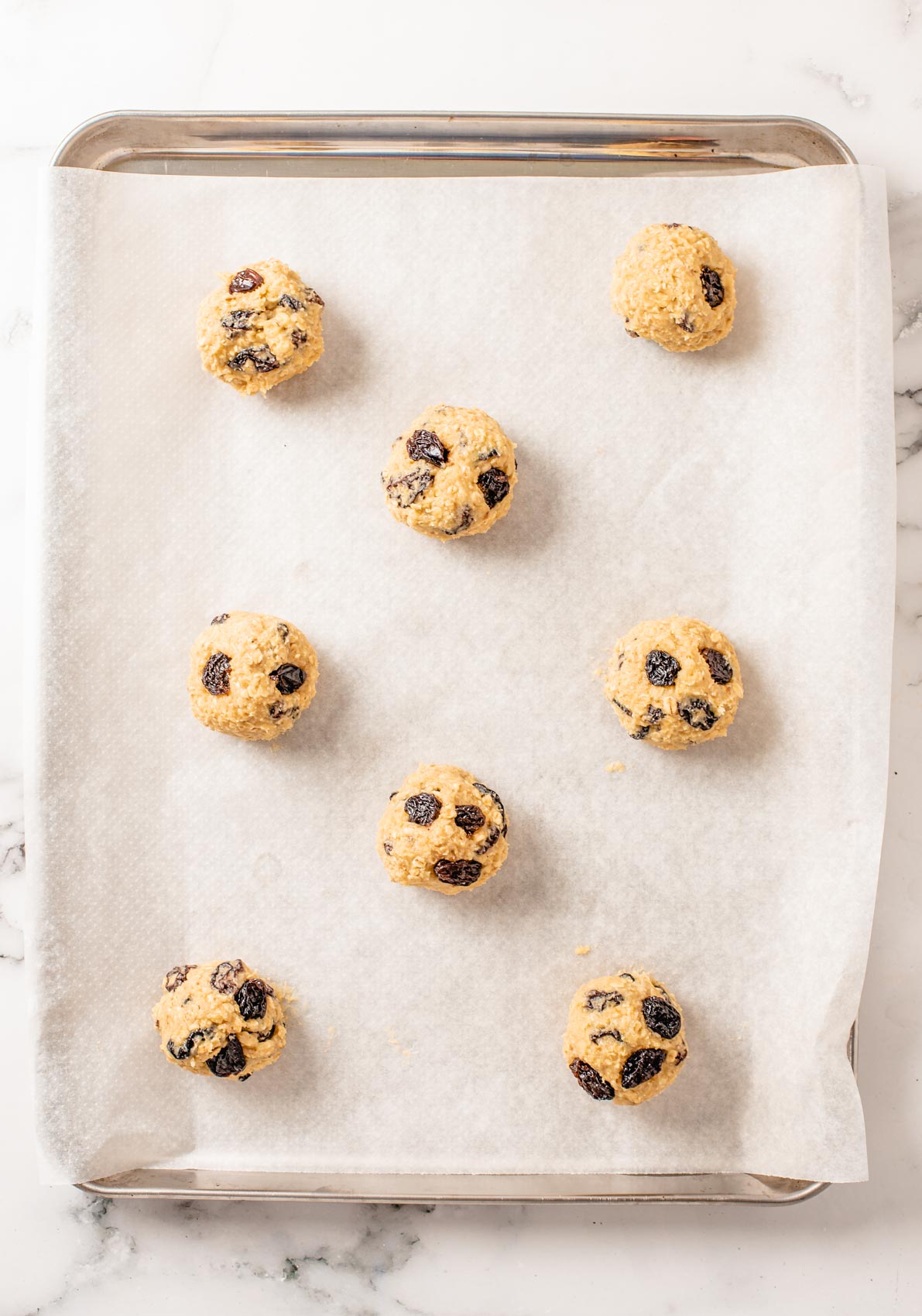 cookie balls placed on parchment paper on baking sheet