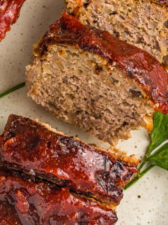 loaf of turkey meatloaf with a vibrant red glaze next to parsley garnish