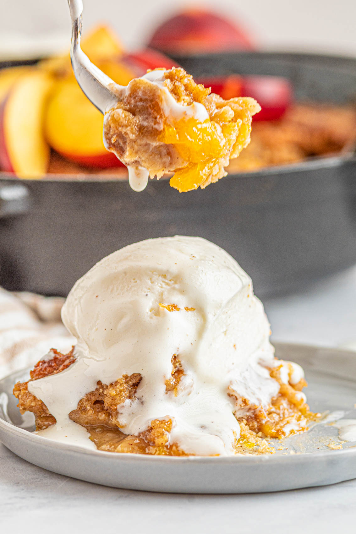 melting ice cream on top of peach cobbler scoop on a plate
