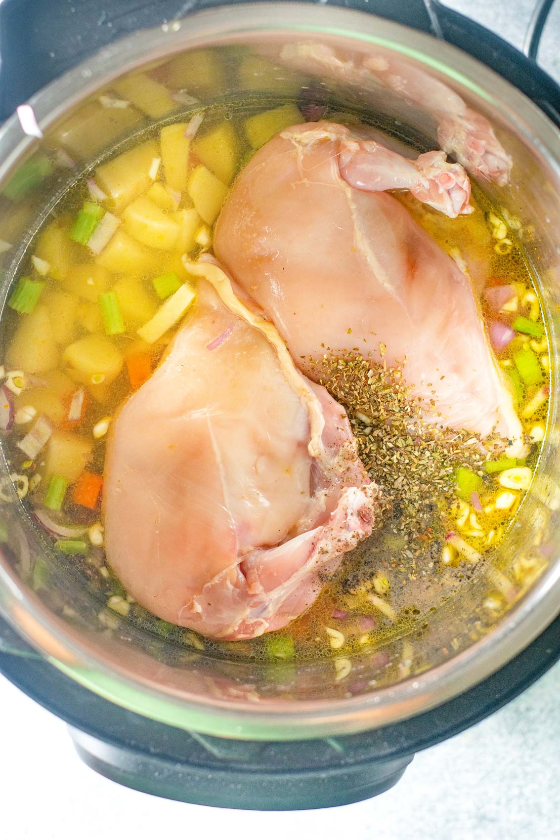chicken pot pie ingredients going in to the instant pot with chicken broth