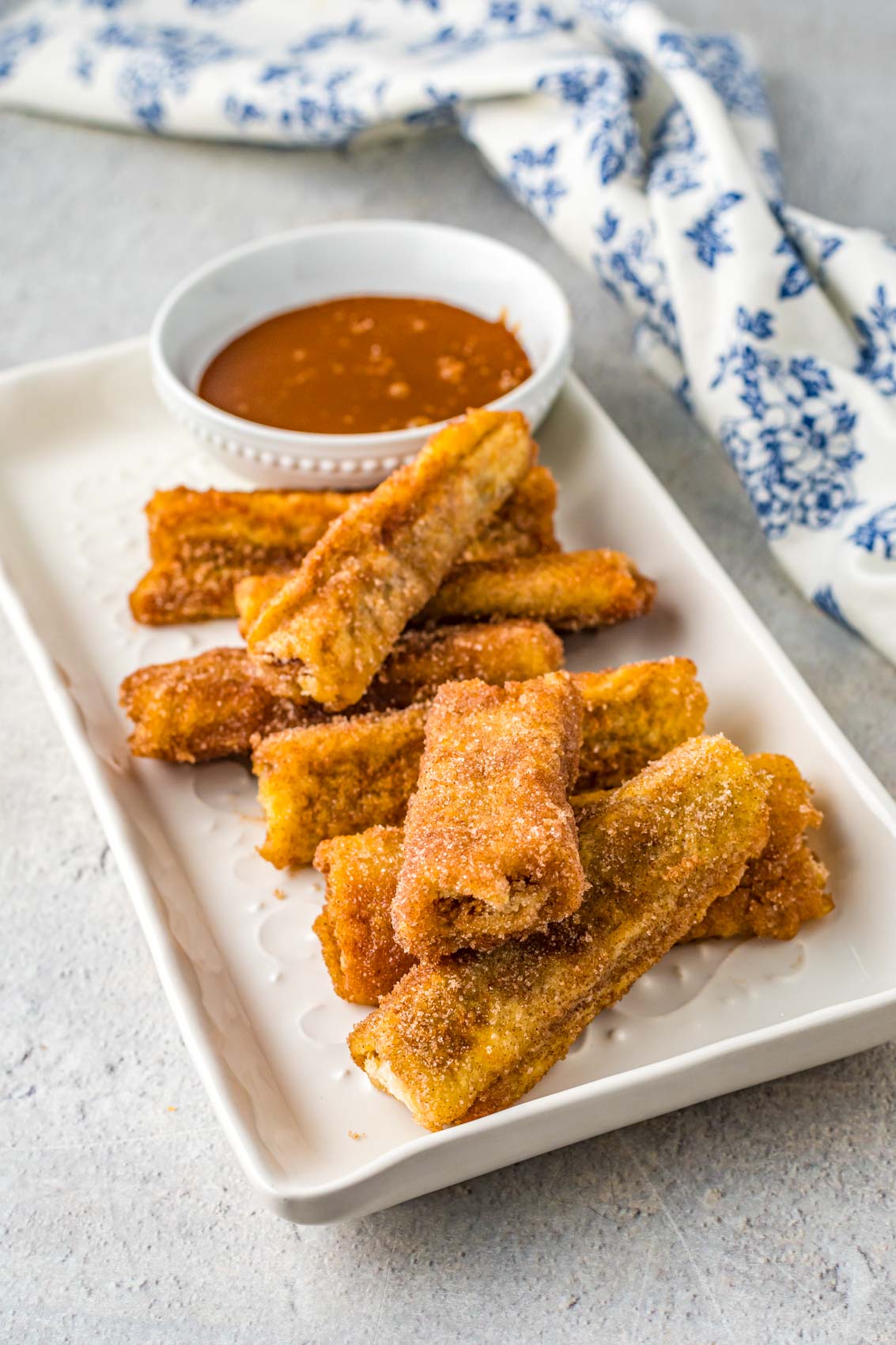 platter of churro french toast rolls with dulce de leche syrup