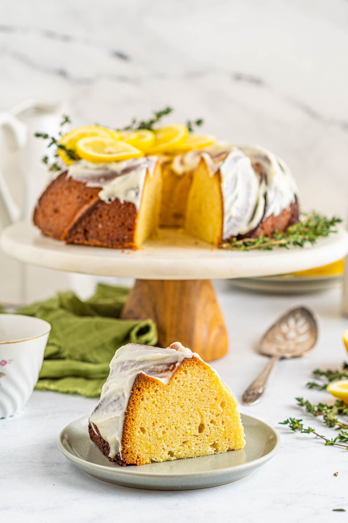 piece of lemon bundt pound cake in front of a cake stand with old spoon