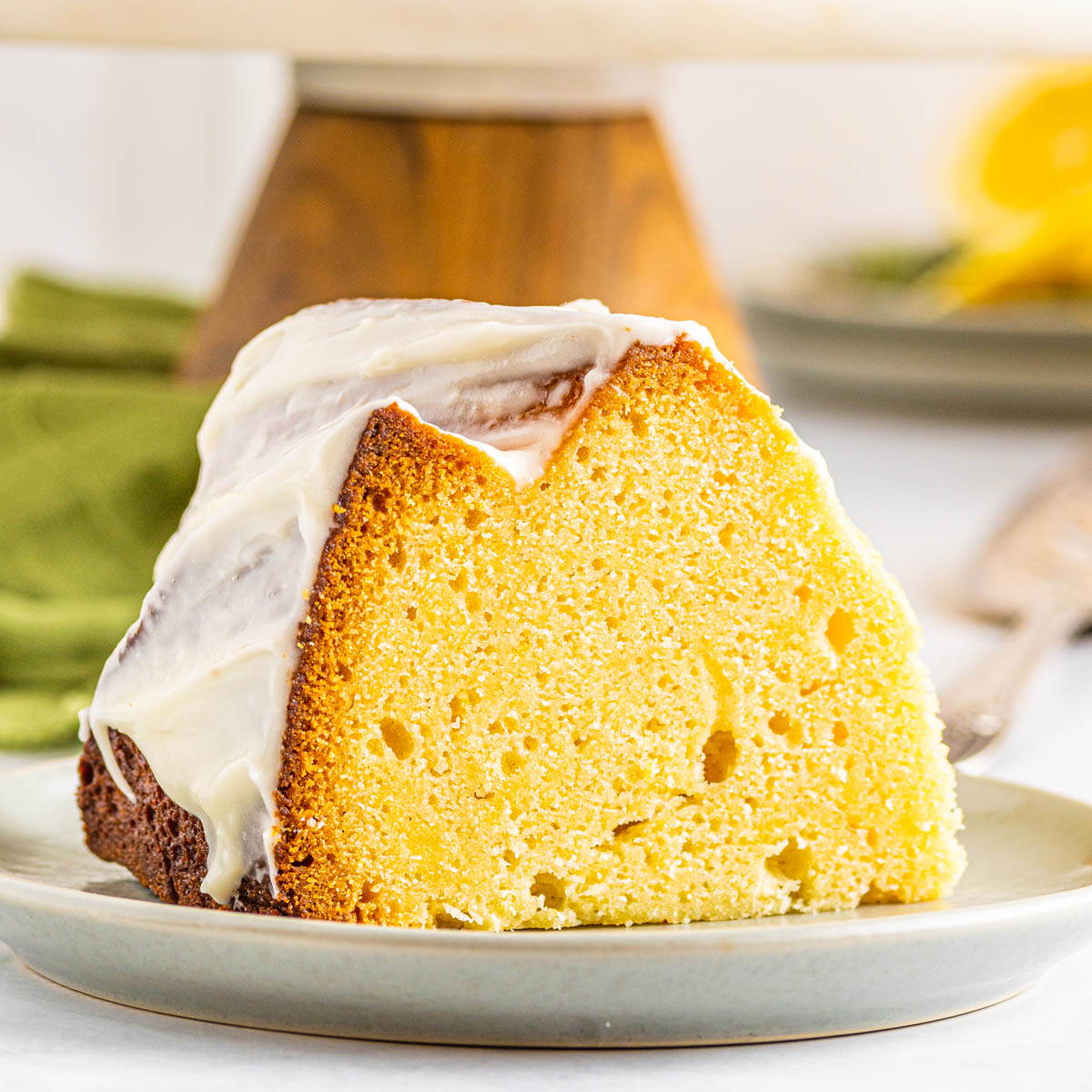 lemon pound cake on a white plate covered in cream cheese frosting