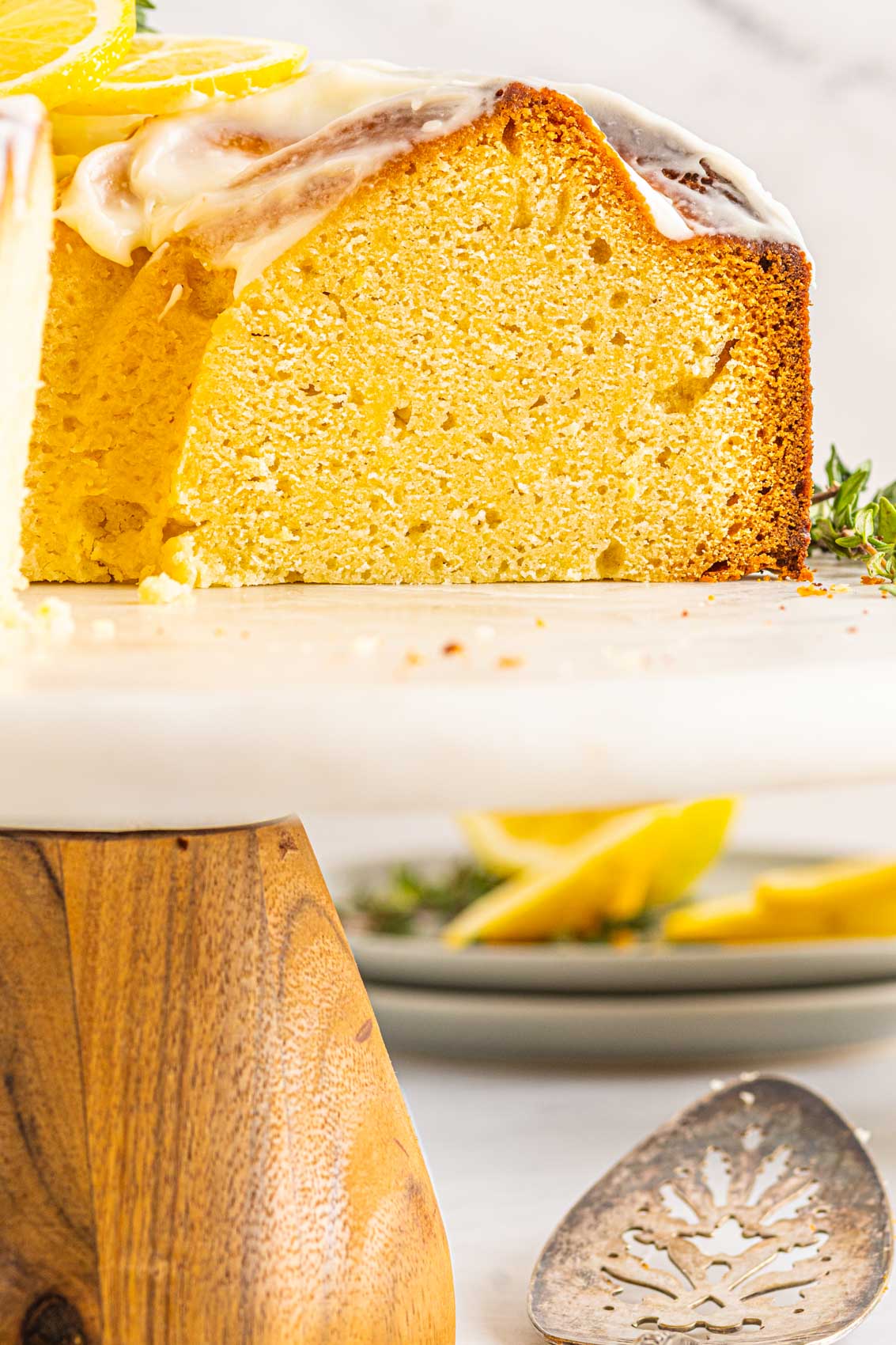 lemon bundt cake with a piece missing and lemon slices on the table