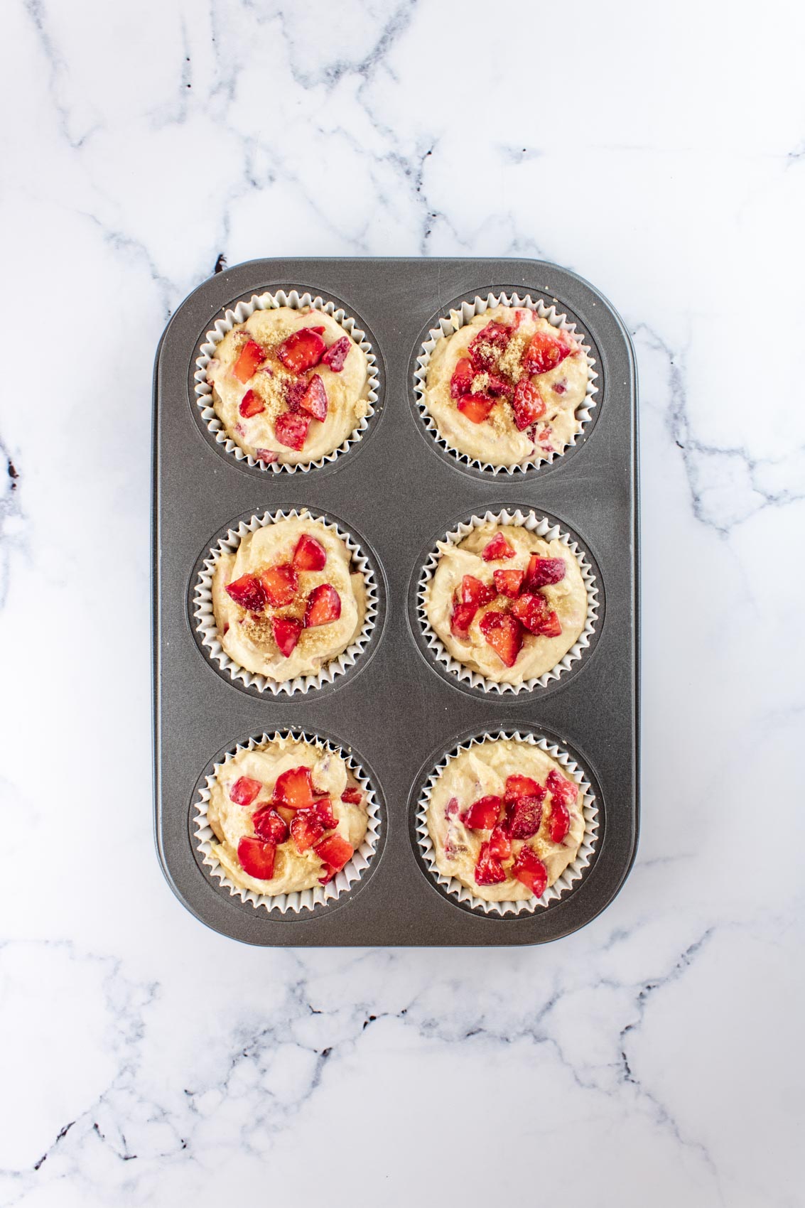strawberry mix added to a greased muffin tin with liners
