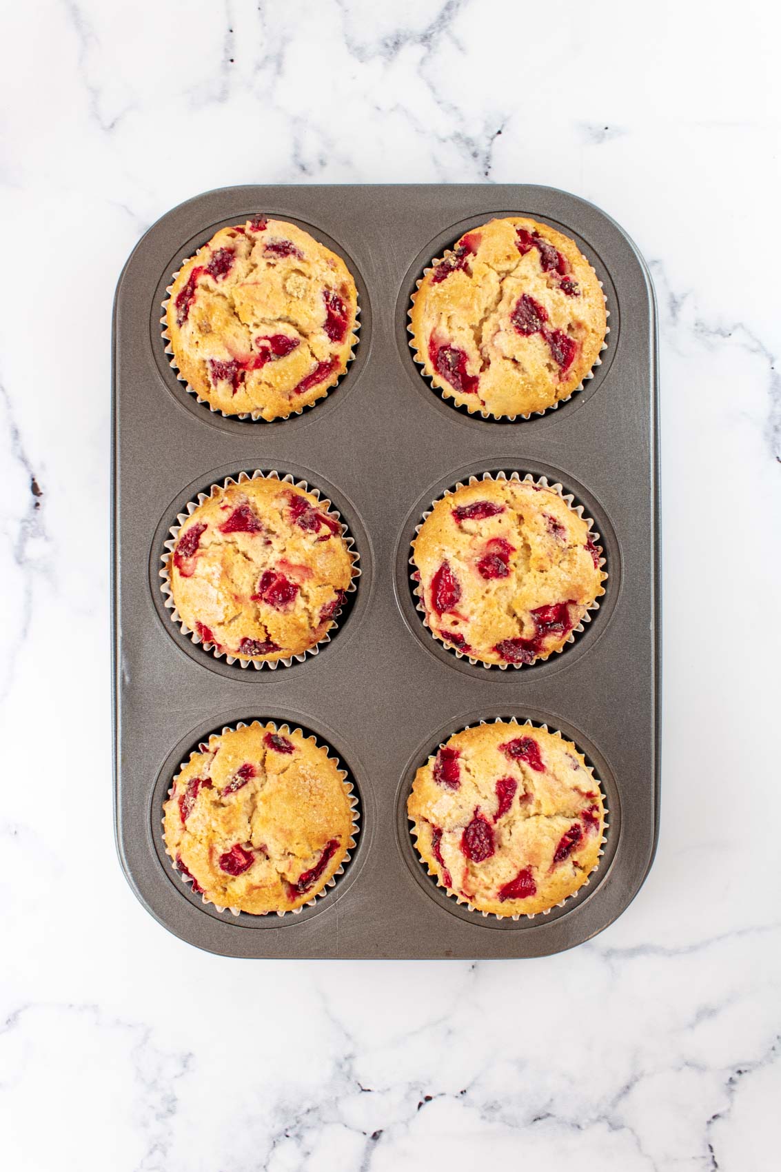 golden strawberry muffins baked inside a muffin tin