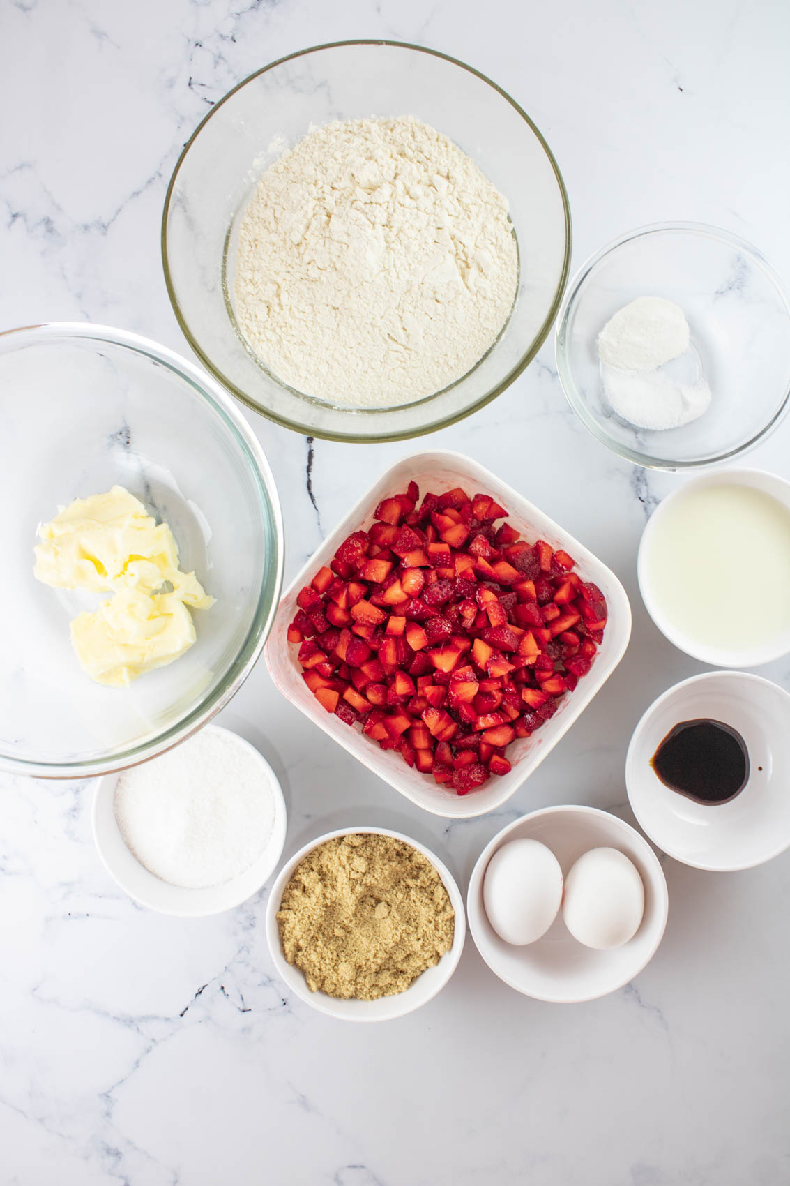 ingredients for strawberry muffins, including fresh strawberries, flour, eggs, butter, brown sugar, powdered sugar