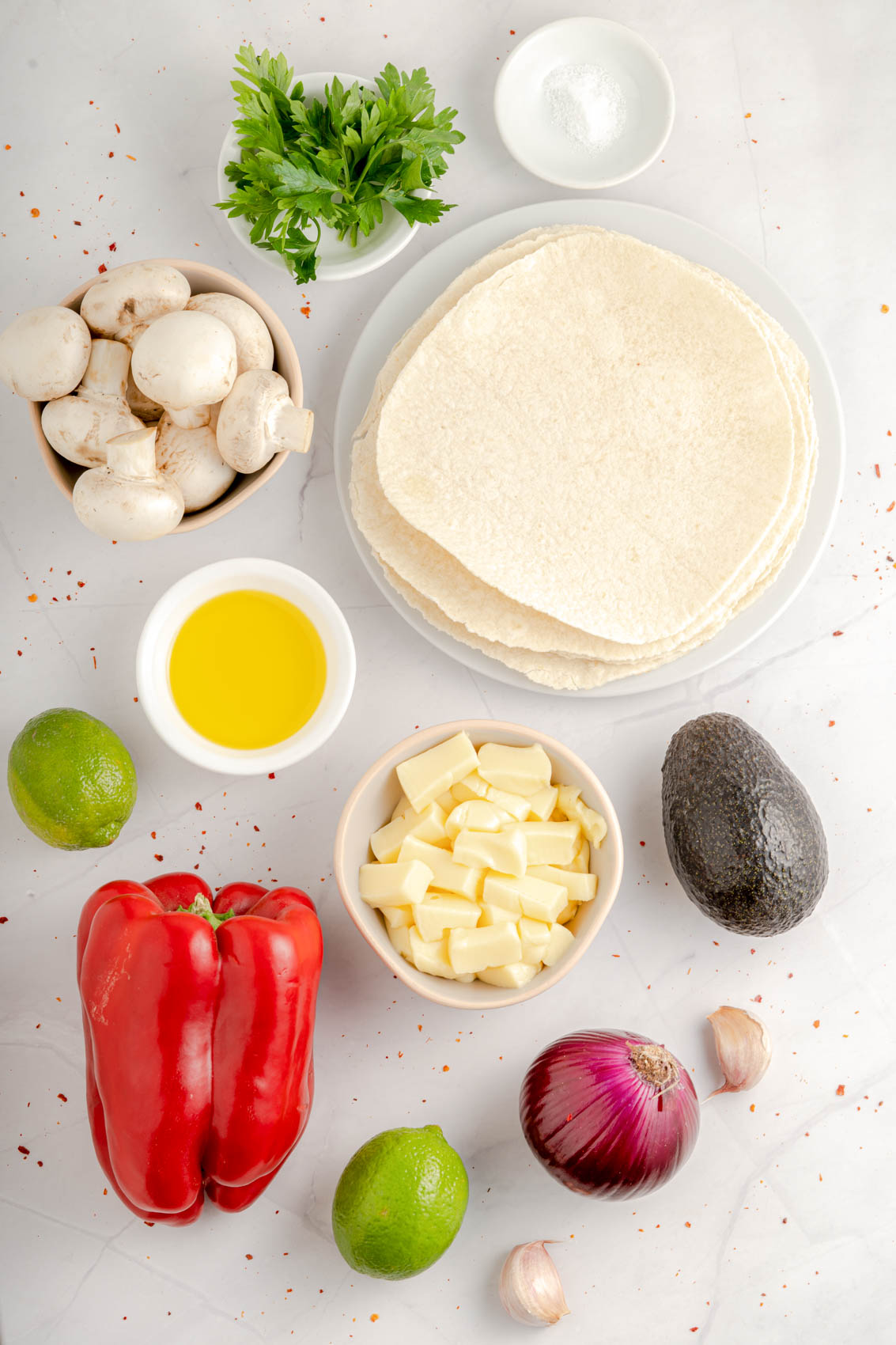 quesadilla ingredients, including red pepper, tortillas, garlic, butter, avocado, red onion, mushrooms, lime and cilantro