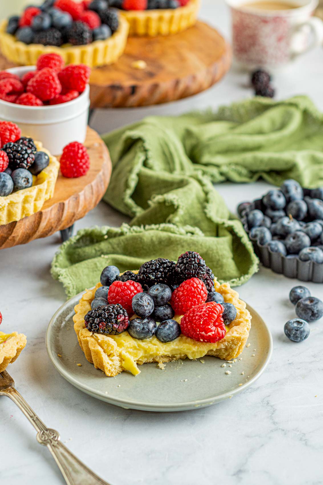 tartlet with berries on top and blueberries scattered about the table