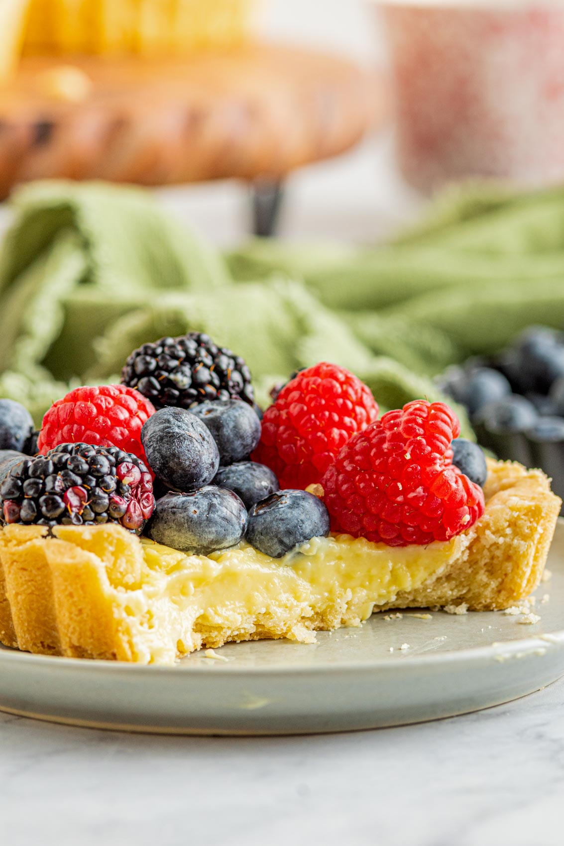 fresh berries on a custard tartlet exposing the gooey insides