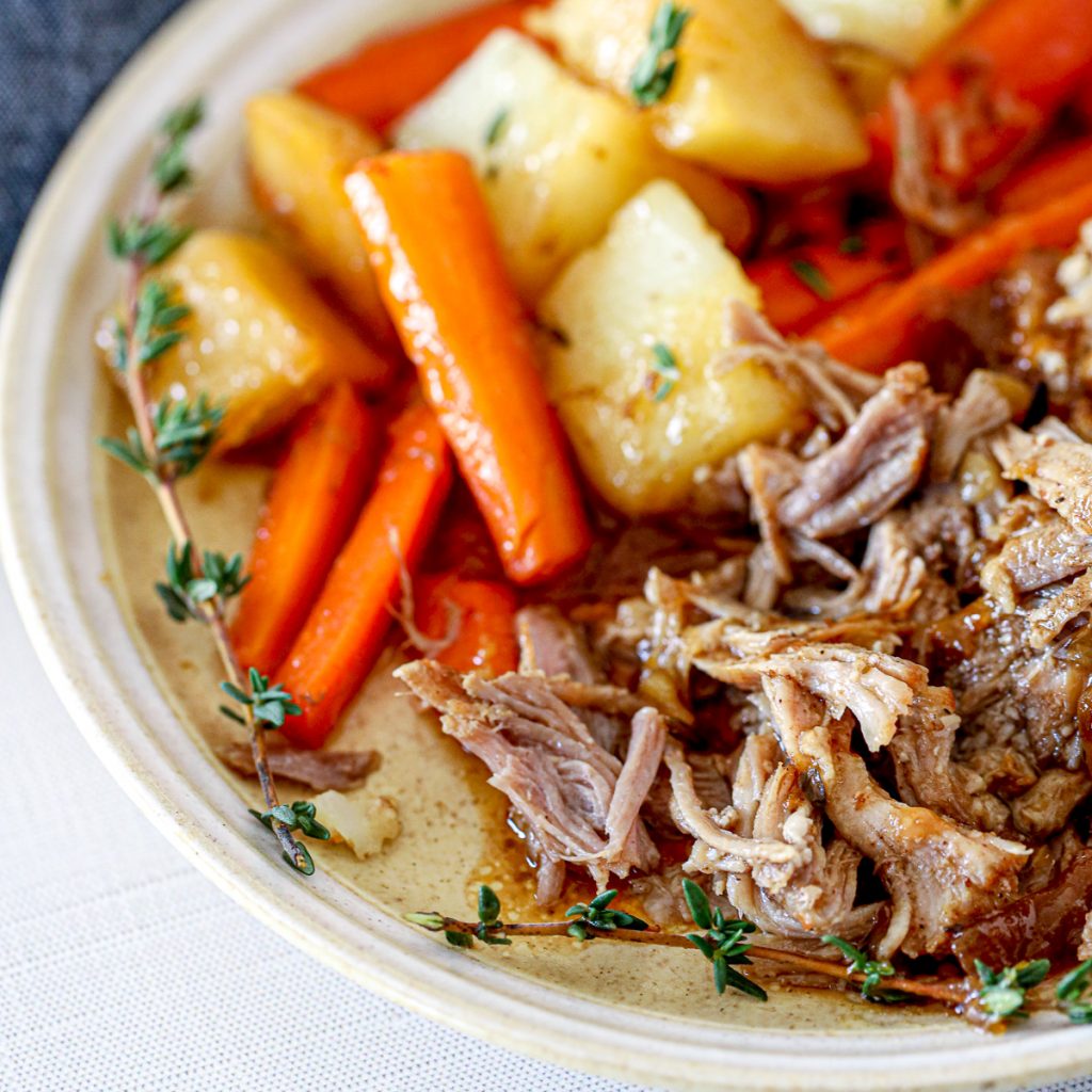 tender pork roast next to glazed carrots and potatoes