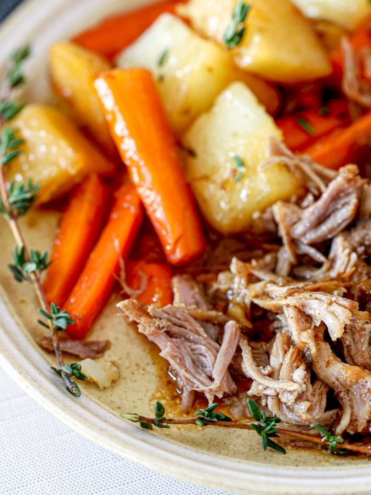 tender pork roast next to glazed carrots and potatoes