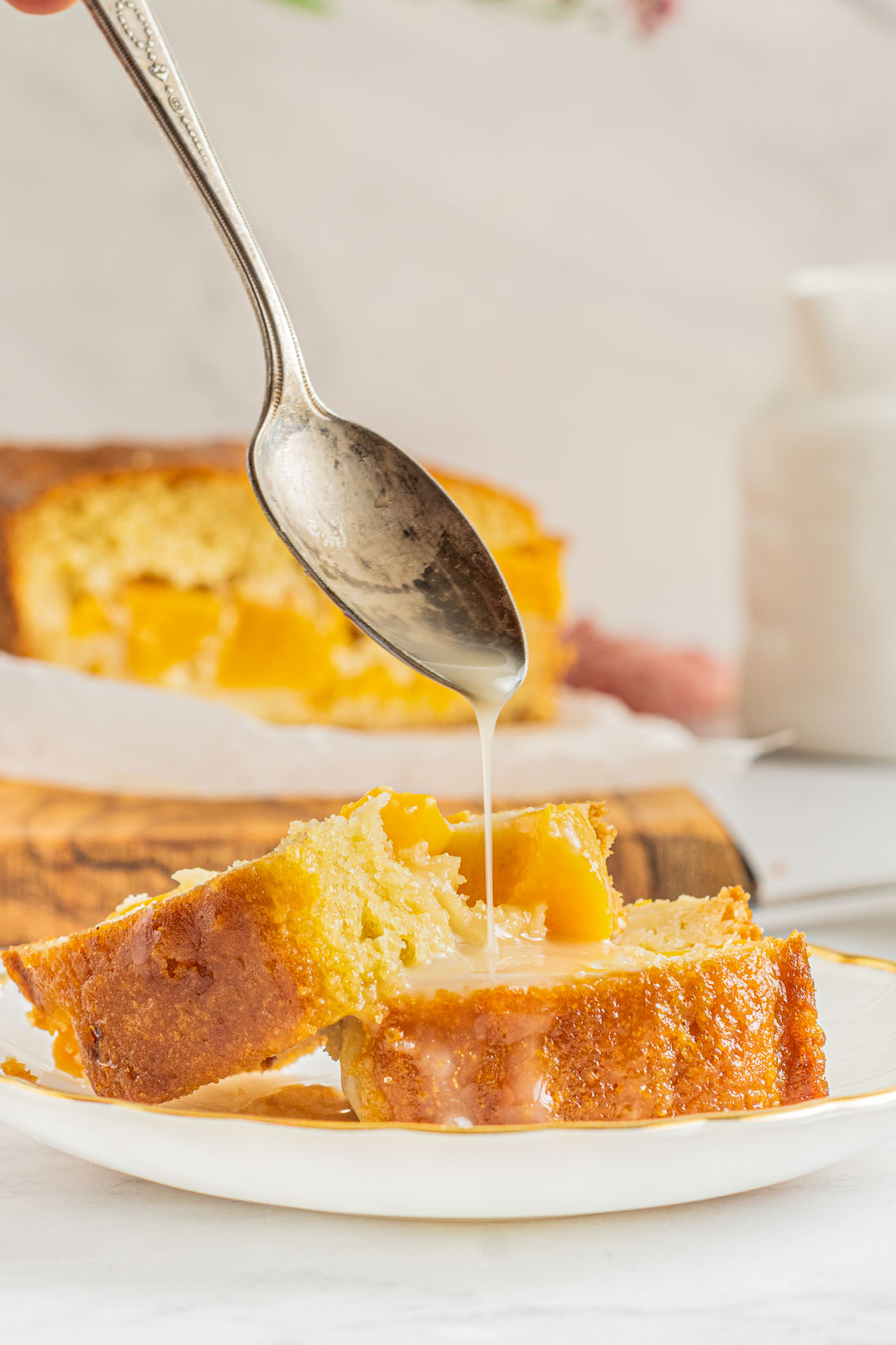 glaze being poured from a spoon onto sweet peach bread