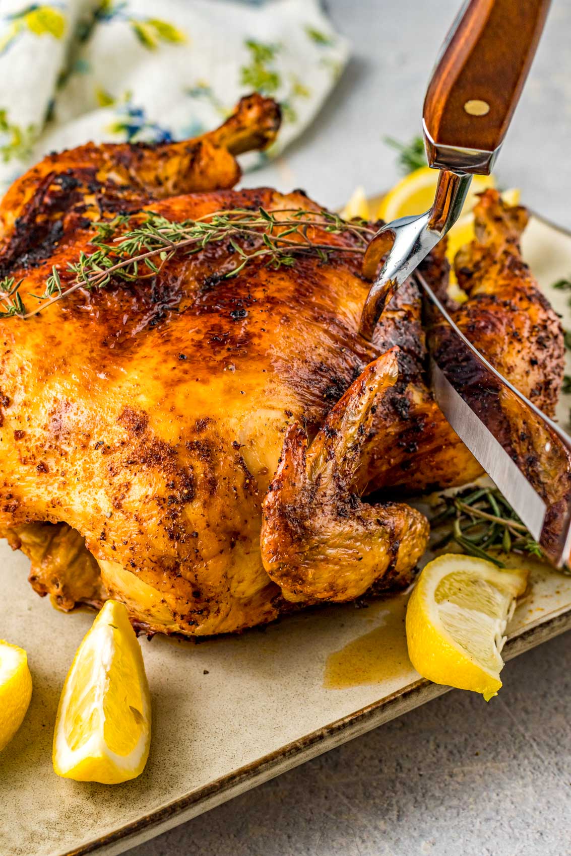 cutting into a golden, juicy chicken with herbs around
